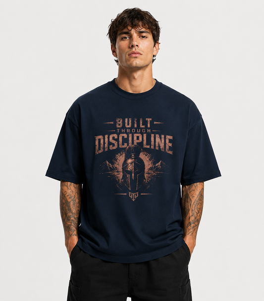 Man wearing a navy blue t-shirt with 'Built Through Discipline' graphic design on a plain background