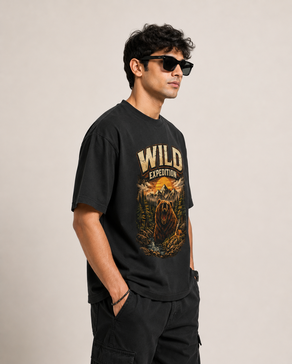 Man wearing a black t-shirt with 'Wild Expedition' design on a beige background