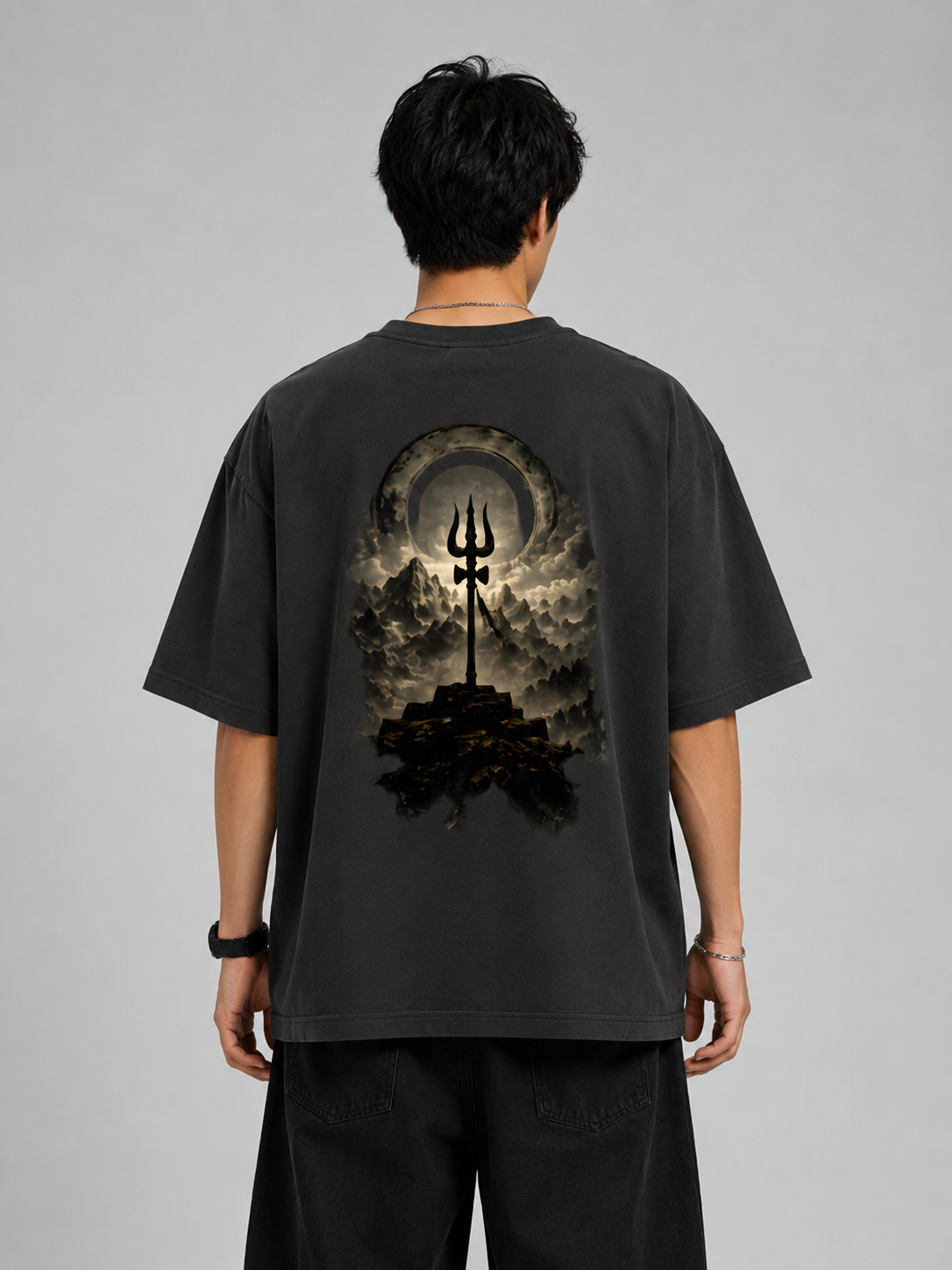 Person wearing a black t-shirt with a graphic design on the back against a gray background