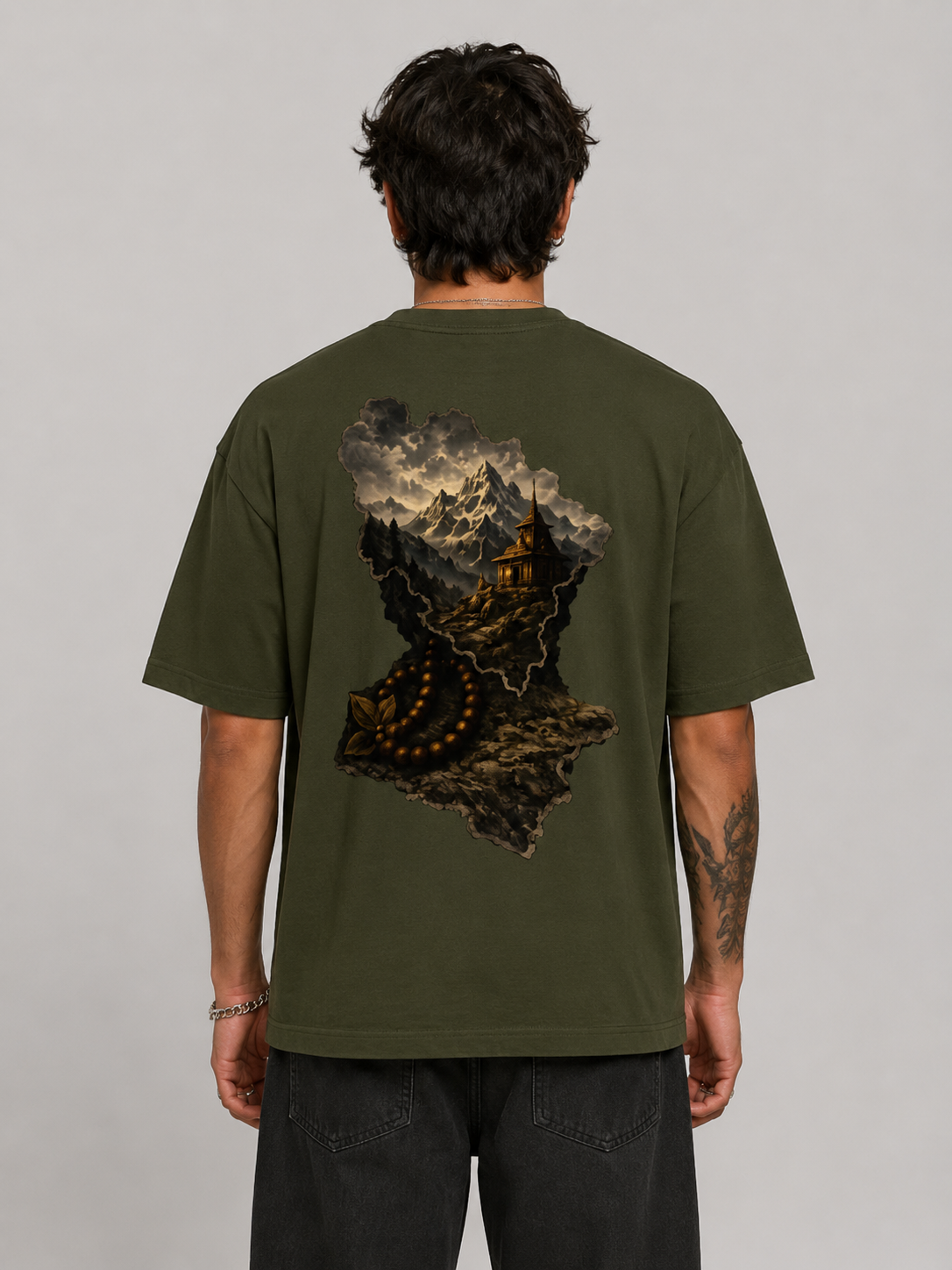 Person wearing a green t-shirt with a mountain graphic on the back against a gray background