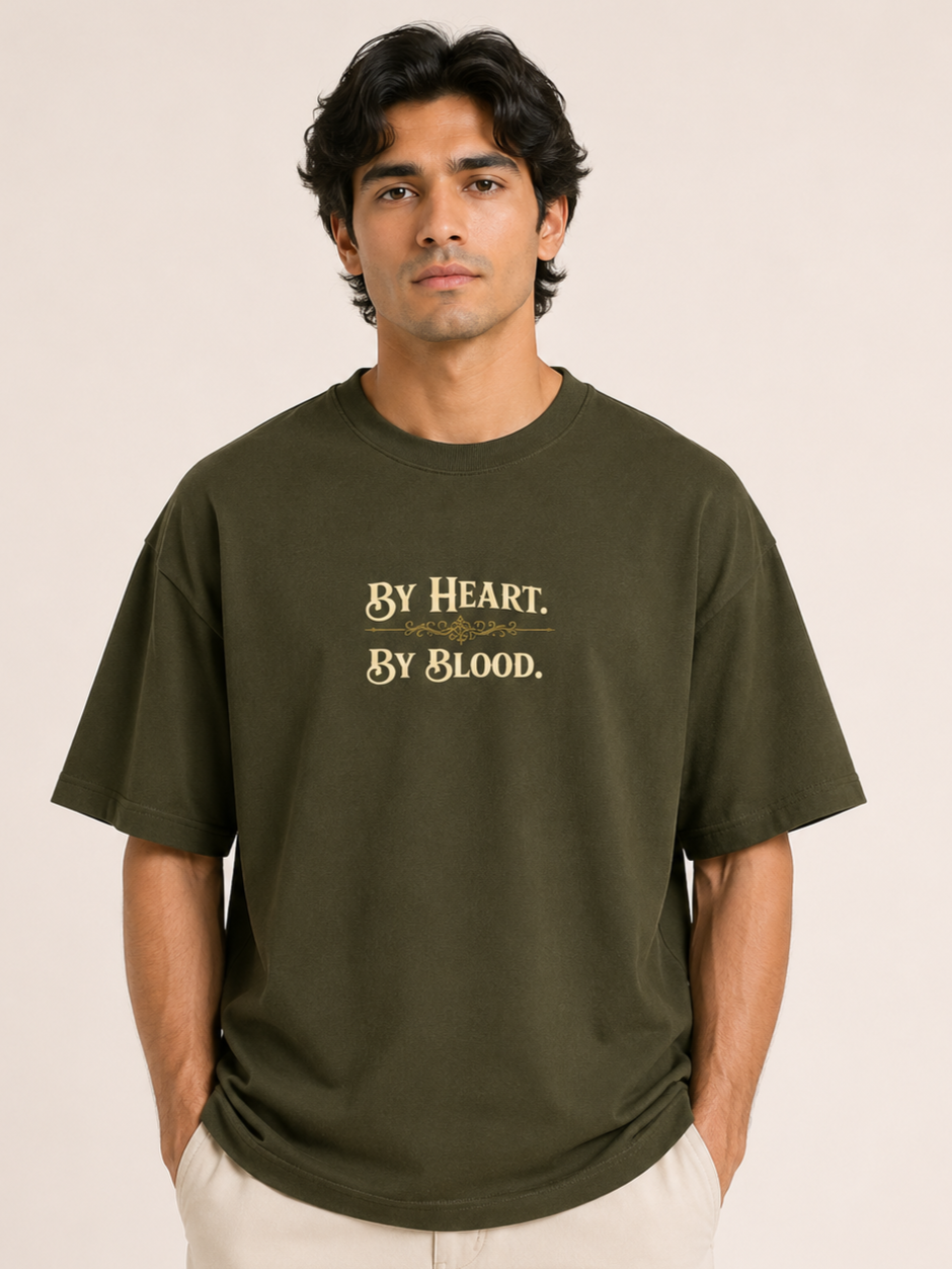 Man wearing a green t-shirt with text 'By Heart, By Blood' on a beige background