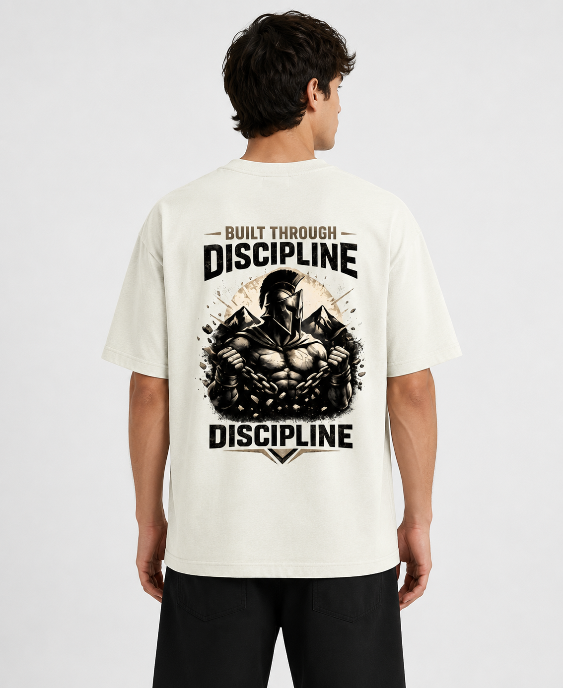Person wearing a white t-shirt with a graphic and text on the back, standing against a plain background.